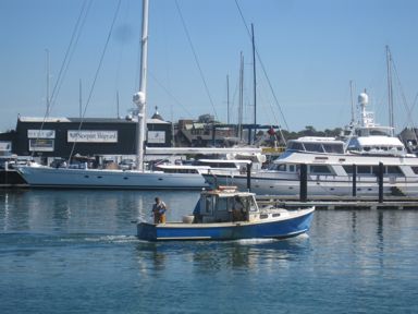 Lobsterman in Newport Harbor with mega yachts behind, Newport, RI